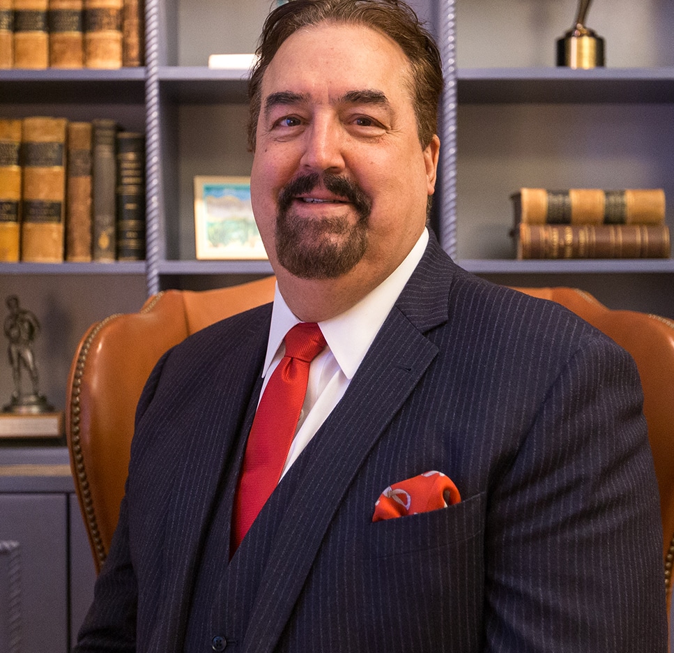 Headshot of man in suit smiling in his office with several historical medical books in the background