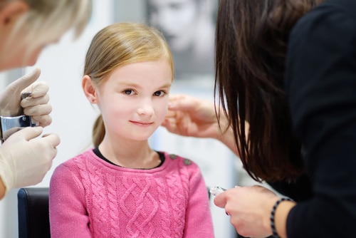 Adorable little girl having ear piercing