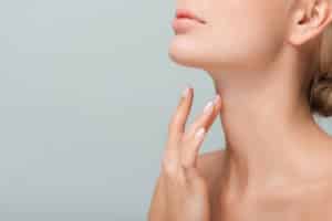 cropped view of woman touching neck isolated on grey