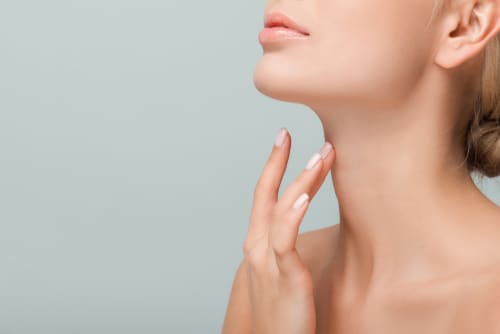 cropped view of woman touching neck isolated on grey