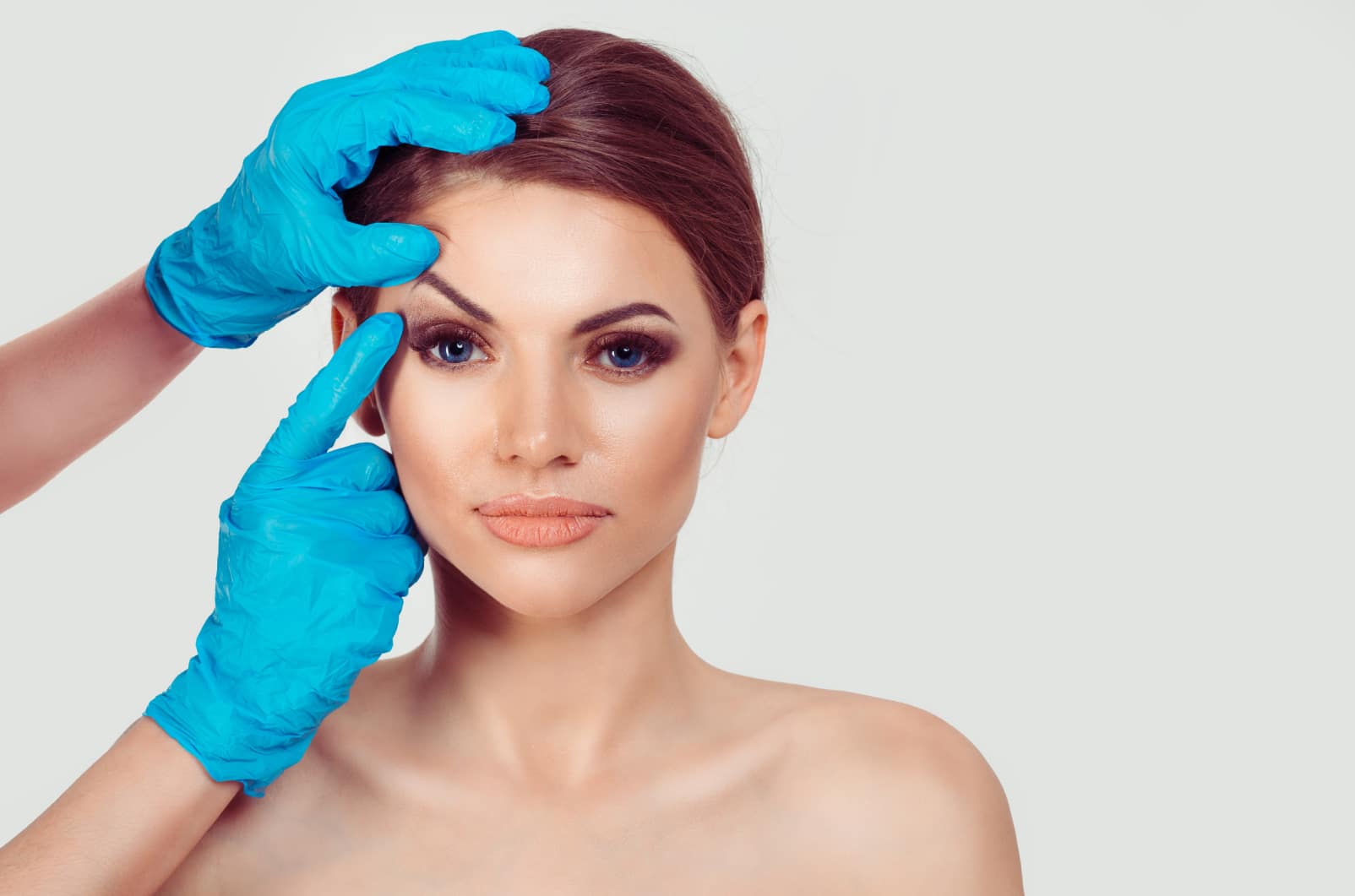 A doctor examining a woman’s upper eyelid before blepharoplasty surgery
